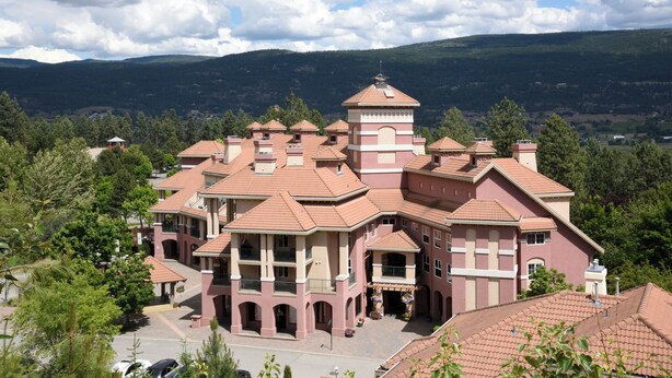 A large, multi-story building with a symmetrical facade, multiple balconies, and a central tower. - Quiet Studio on Golf Course - 212B (Kelowna)