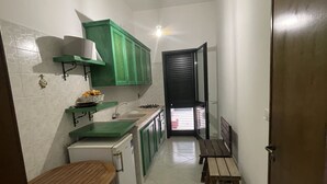 Une cuisine compacte avec des meubles verts, un plan de travail blanc et une petite table à manger.