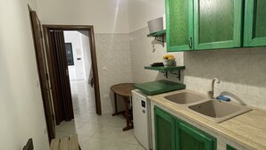 Une cuisine avec des meubles de rangement verts, un évier et un petit réfrigérateur.