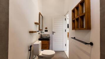 A narrow bathroom with a toilet, sink, and wooden shelves.