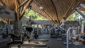 Una palestra con diverse attrezzature per esercizi, tra cui panche, macchinari per pesi e pesi liberi.