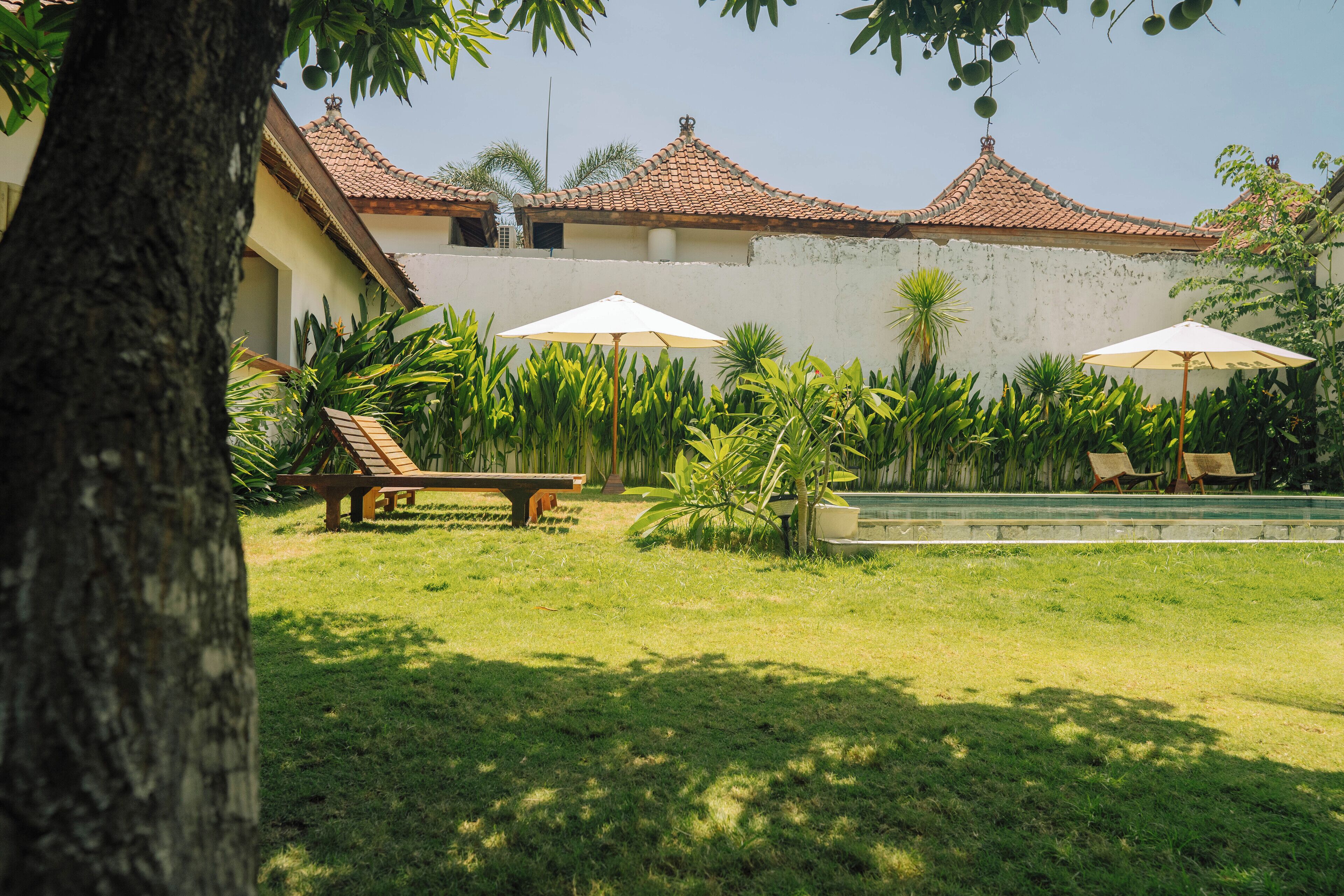 Un patio con piscina, sillas de descanso y sombrillas.