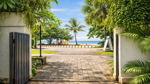 Un sendero pavimentado que conduce a una playa con palmeras y vistas al océano.