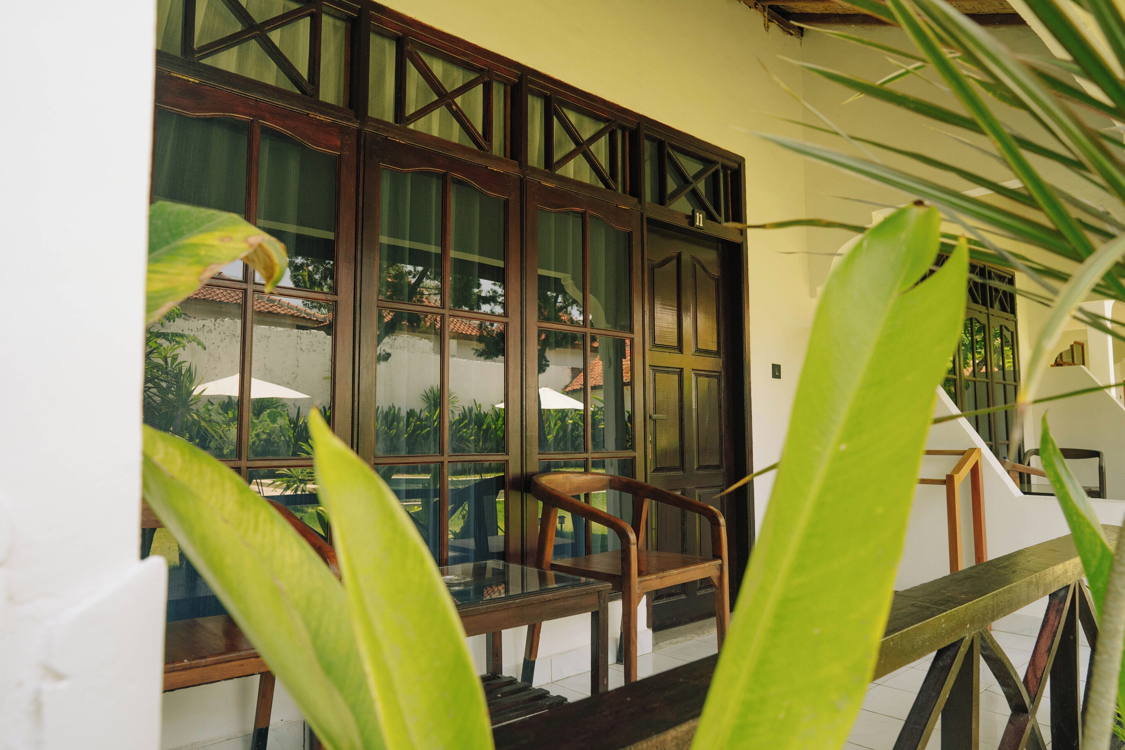 A room with a large window, wooden furniture, and a view of greenery outside.