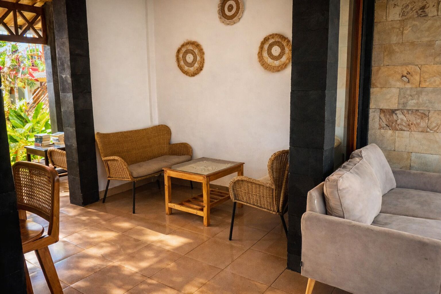 Un coin salon confortable avec un canapé, deux fauteuils et une petite table, offrant une vue sur la verdure environnante.