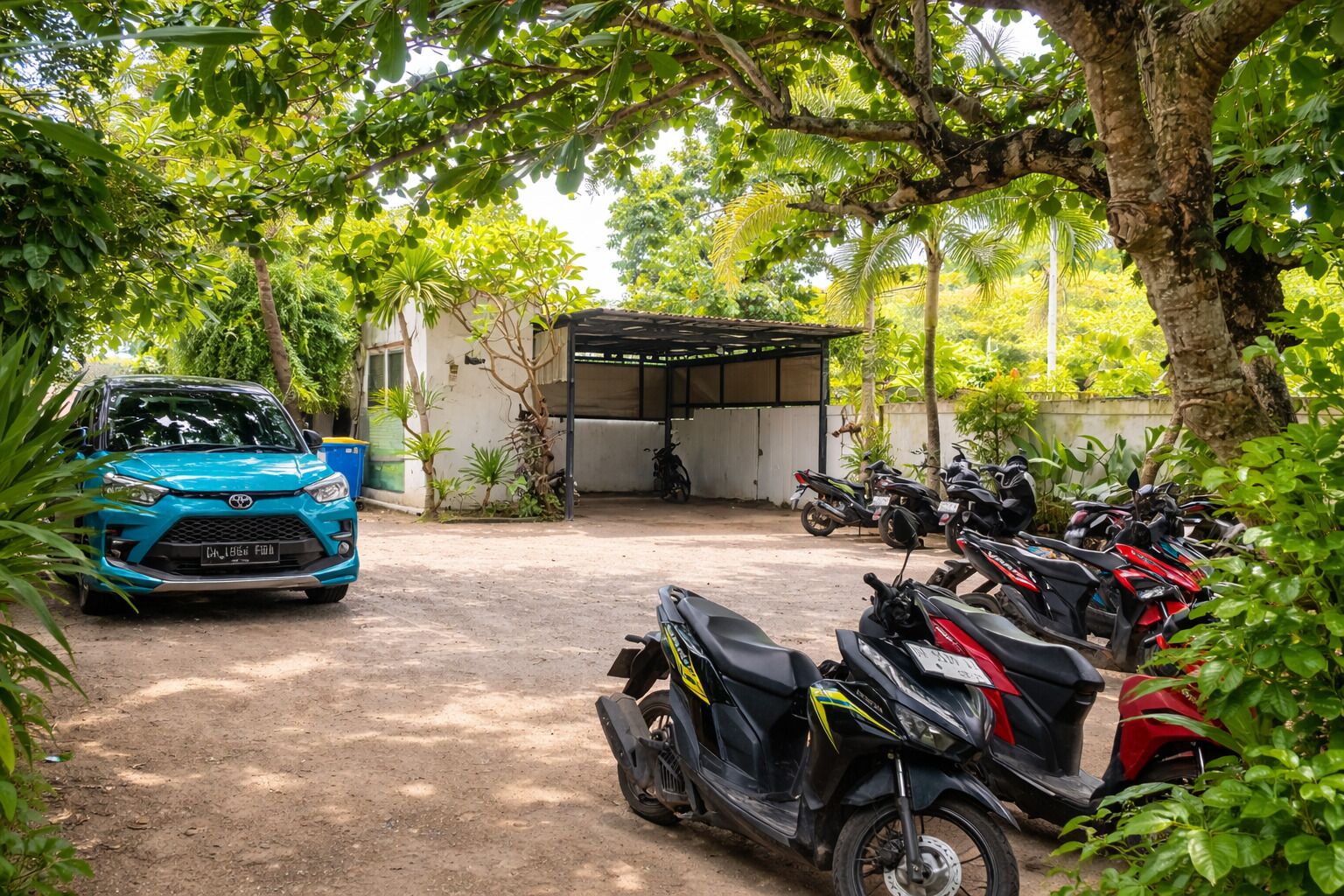 Un área de estacionamiento con un coche azul y varias motocicletas.