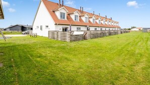 A row of white houses with red roofs and wooden fences.