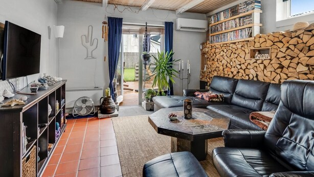 A modern living room with a leather sofa, a coffee table, and a bookshelf filled with books.