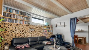 A cozy living room with a black leather sofa, a stone coffee table, and a bookshelf filled with books.