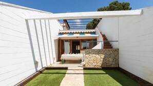 Uma casa moderna com parede de pedra, escada de madeira e área de estar coberta ao ar livre.