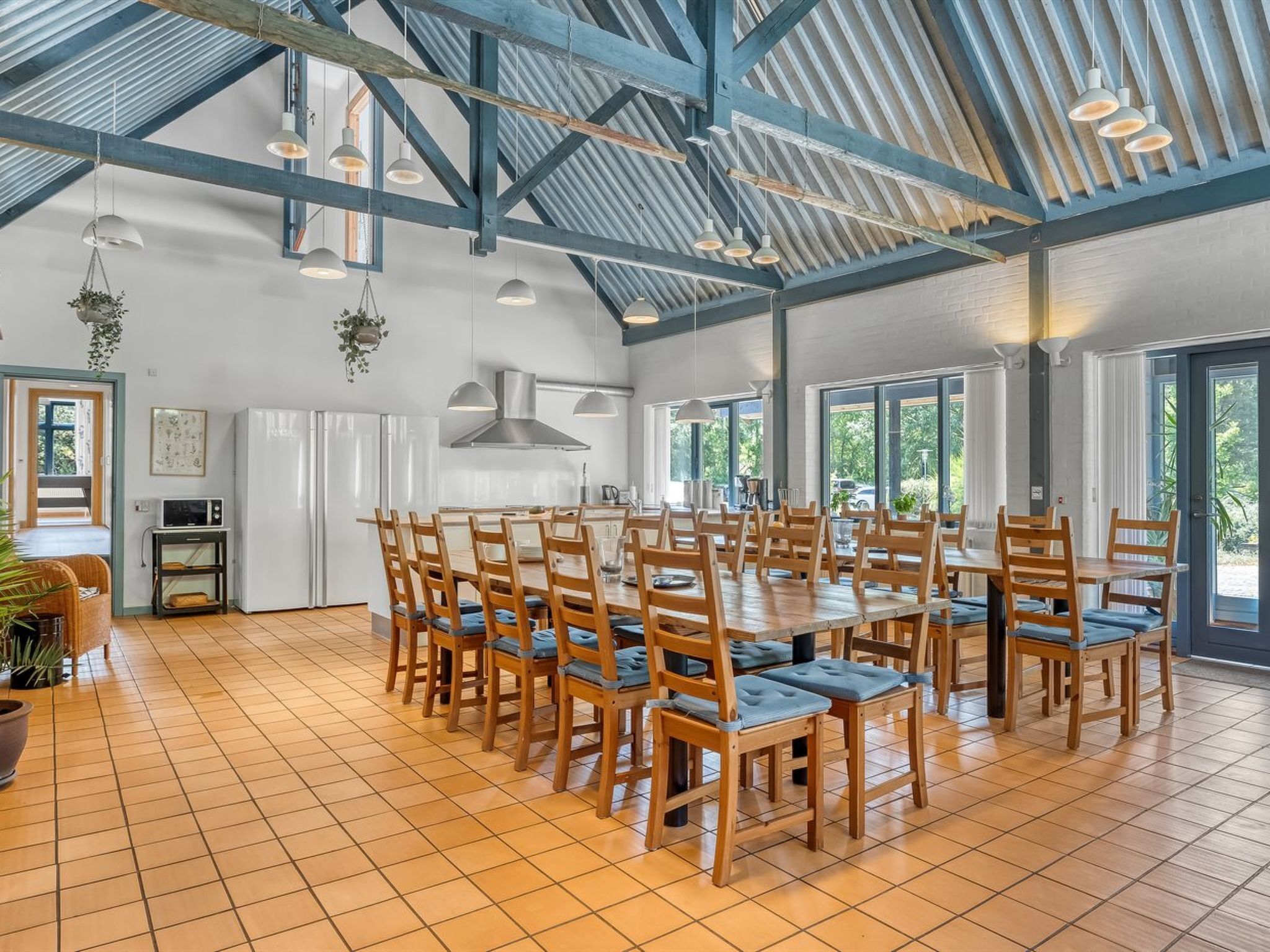 A spacious dining area with a high ceiling and exposed beams, surrounded by large windows.