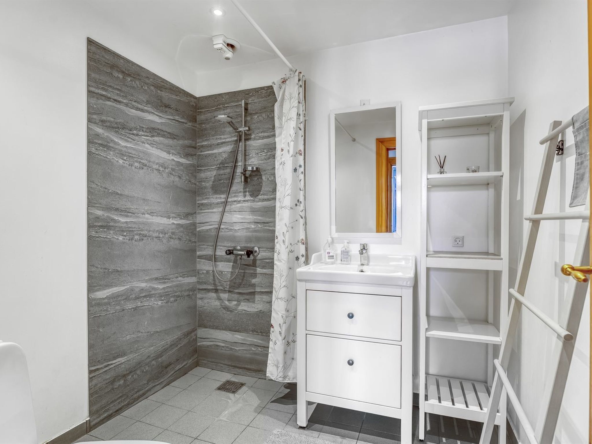 A bathroom with a shower, a sink, and a vanity with drawers.