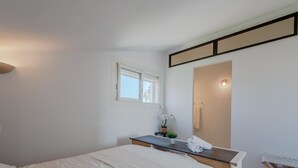 A bedroom with a bed, a bedside table with a lamp, a small window, and a mirror. - Pine's Mansion by Interhome (Le Barcarès)
