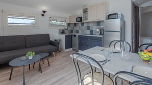 A compact kitchen with a dining area, a sofa, and a small table with a plant. - Pine's Mansion by Interhome (Le Barcarès)