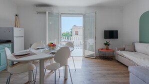 A modern apartment with a dining area, a sofa, a TV, and a balcony with a view of buildings. - Pine's Mansion by Interhome (Le Barcarès)