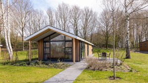 A modern building with large windows, a covered walkway, and a garden area with benches. - Scenic Retreat by the Lake (Hoge Hexel)