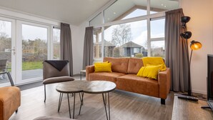 A spacious living room with a large window, a sofa, a chair, and a coffee table. - Scenic Retreat by the Lake (Hoge Hexel)