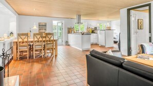 A spacious kitchen with a dining area, a living room with a sofa, and a view of the outdoors.