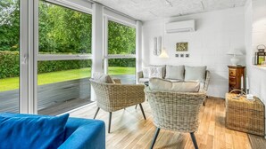 A spacious living area with large windows, wicker furniture, and a blue sofa.