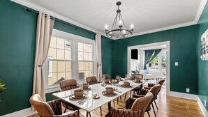 Ein Esszimmer mit einem langen Tisch, gedeckt für sechs Personen, umgeben von gepolsterten Stühlen.