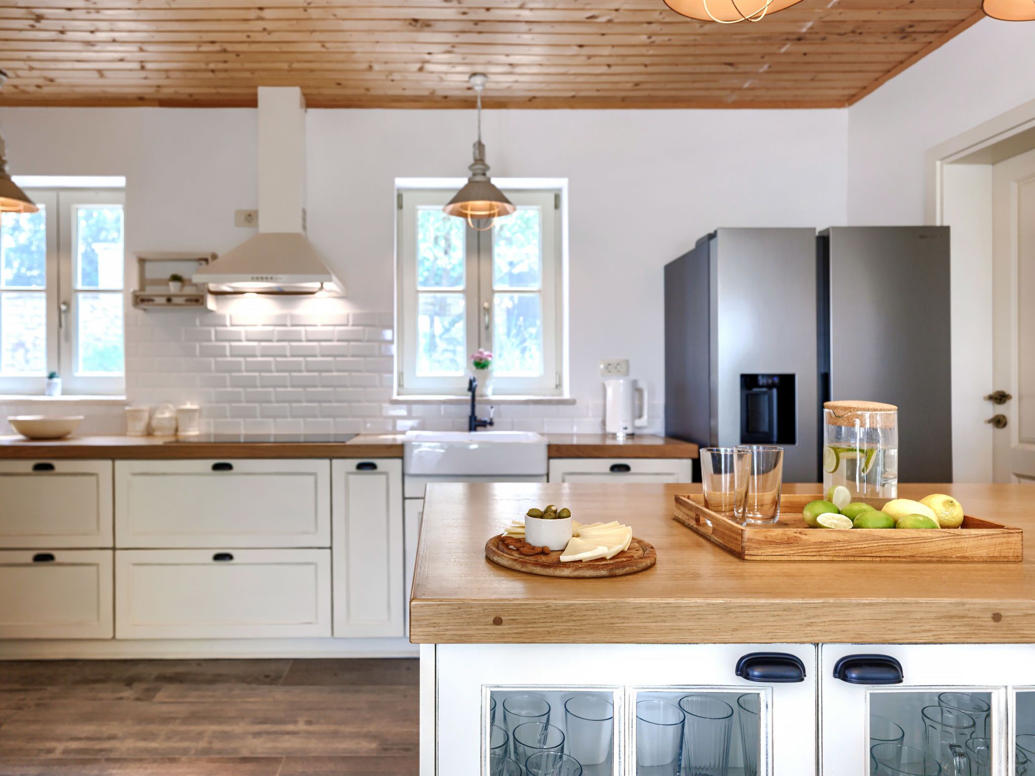 A modern kitchen with white cabinets, a wooden countertop, a built-in oven, and a window providing natural light.