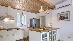 A modern kitchen with white cabinetry, a wooden island, and pendant lighting. - Ardiletta by Interhome (Poreč/Baderna)