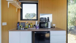 A compact kitchen with a sink, a microwave, and a dishwasher. - Scrub Tiny House by Tiny Away (McLaren Vale)