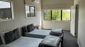 A room with two beds, a window, and an air conditioning unit. - Tranquil retreat in close proximity to Auckland (Ararimu)