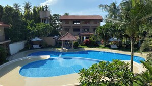 A swimming pool with a circular design, surrounded by well-maintained grass and palm trees. - Sierra Resort  Dauin Negros Oriental (Dauin)