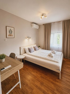 A bedroom with a bed, bedside table, chair, and a desk with a plant.