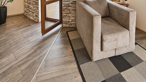 Una habitación con pared de piedra, un sofá, una planta en maceta y vistas a través de un ventanal.