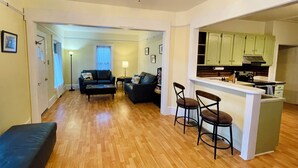 Un salon comprenant un canapé, une table basse et un coin repas avec des tabourets de bar.