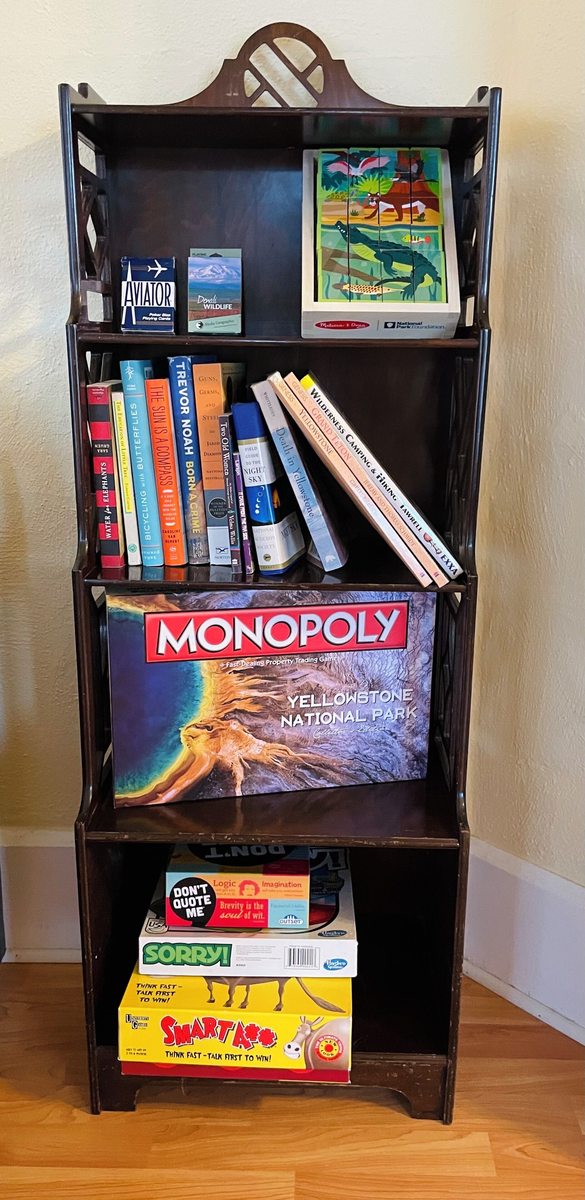 A bookshelf with various books and games, including a Monopoly box.