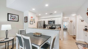 A modern kitchen with white cabinets, stainless steel appliances, and a central island. - Uncapafew more Beachside - Unit 1602 Island Dunes Condos- One block from Beach (Port Aransas)