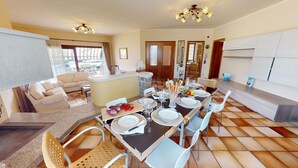 A dining area with a table set for four, a sofa, and a kitchen area with a counter and cabinets.