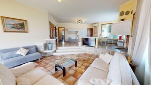 A spacious living area with a sofa, a coffee table, and a TV. There is a kitchen area with a dining table and chairs.