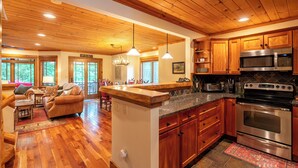 A spacious kitchen with wooden cabinets, a large stove, and a dining area with a sofa and table. - Mountain Retreat - walk to Main Street (Lake Placid)