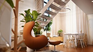 A modern living room with a curved sofa, a dining table with chairs, and a staircase with a white railing. - Garden Pool Villa (Seoul)