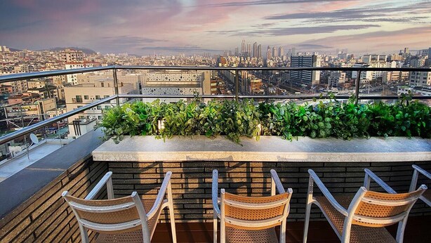 A rooftop bar with a city view, seating area, and a planter with greenery. - Garden Pool Villa (Seoul)