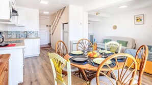 A modern kitchen with white cabinets, a wooden countertop, and a dining area with a round table set for four. - Les Mas de Cogolin by Interhome (Cogolin)