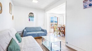 A living room with a sofa, a glass coffee table, and a dining area with chairs and a table. - Les Mas de Cogolin by Interhome (Cogolin)