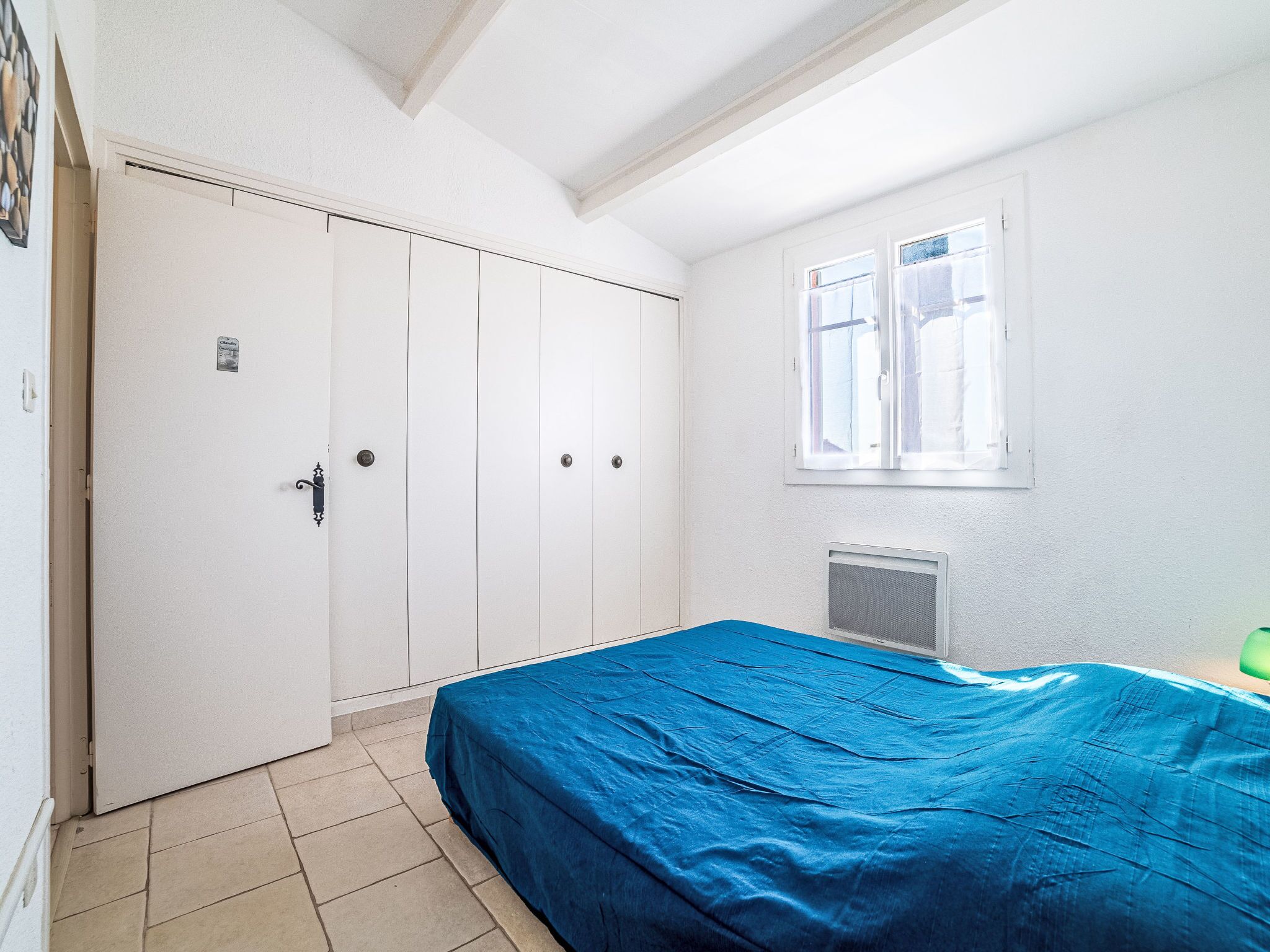 Une pièce comprenant un lit, une armoire, une fenêtre et un radiateur.