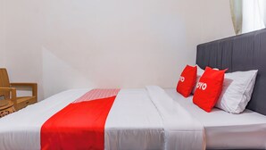 A neatly made bed with a white and red bedspread, two red pillows with "YOYO" text, and a grey headboard. - Hotel O The Roy Suite Guest House (Bandar Lampung)
