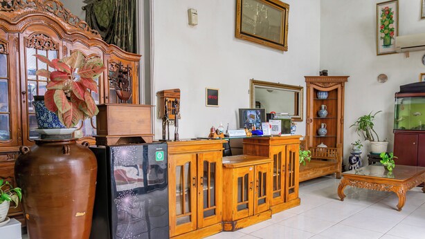A living room with a large vase, a refrigerator, wooden cabinets, a glass coffee table, and a fish tank. - Hotel O The Roy Suite Guest House (Bandar Lampung)