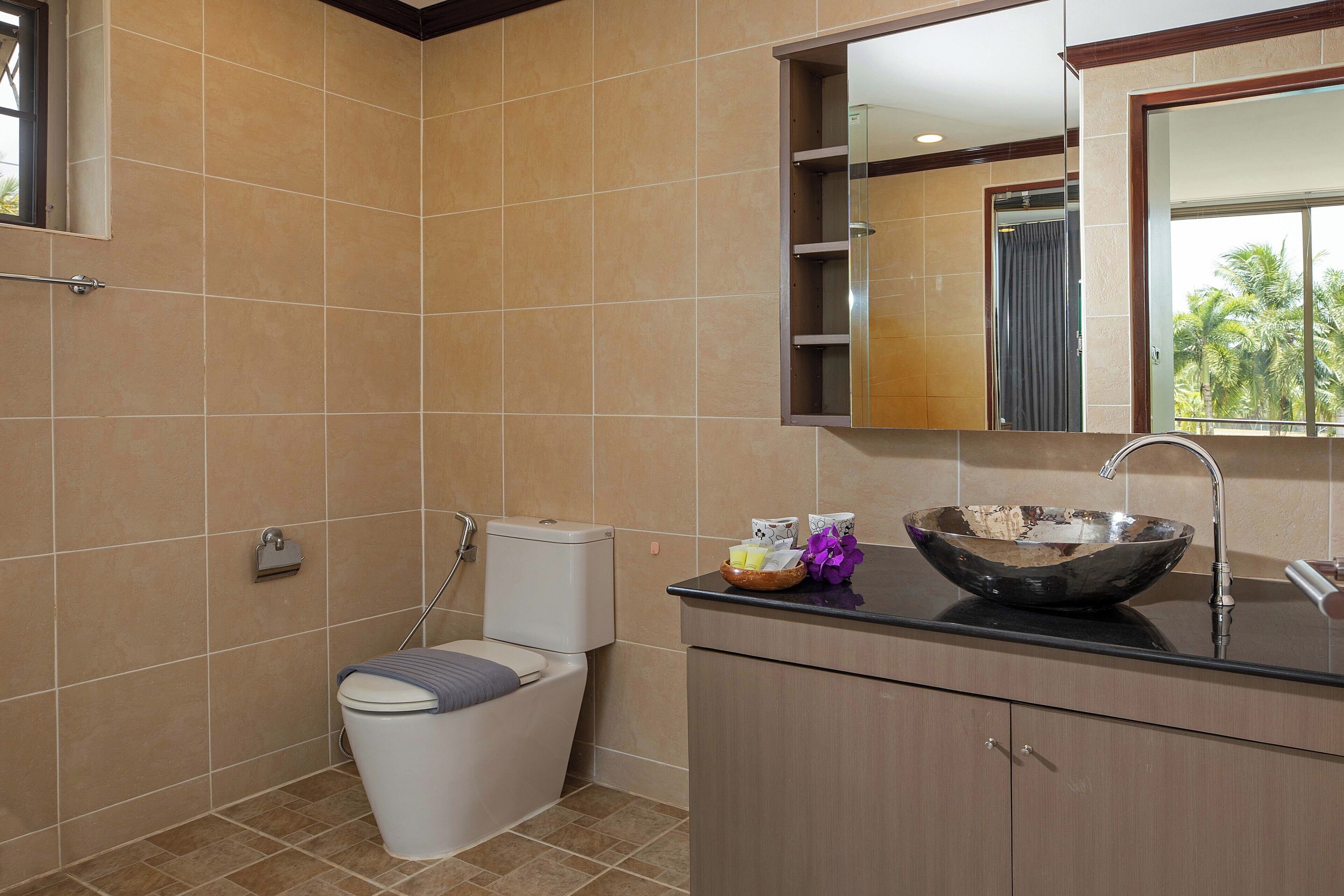 Egy fürdőszoba, amelyben WC, mosdókagyló és tükör található.