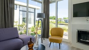 Ein modernes Wohnzimmer mit einer Couch, einem gelben Sessel, einem runden Tisch und einem Kamin.