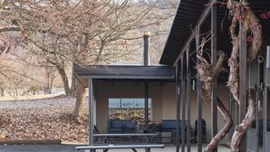 An outdoor patio area with picnic tables and benches, a covered seating area, and a distinctive sculptural tree trunk. - Alpine Inn (Khancoban)
