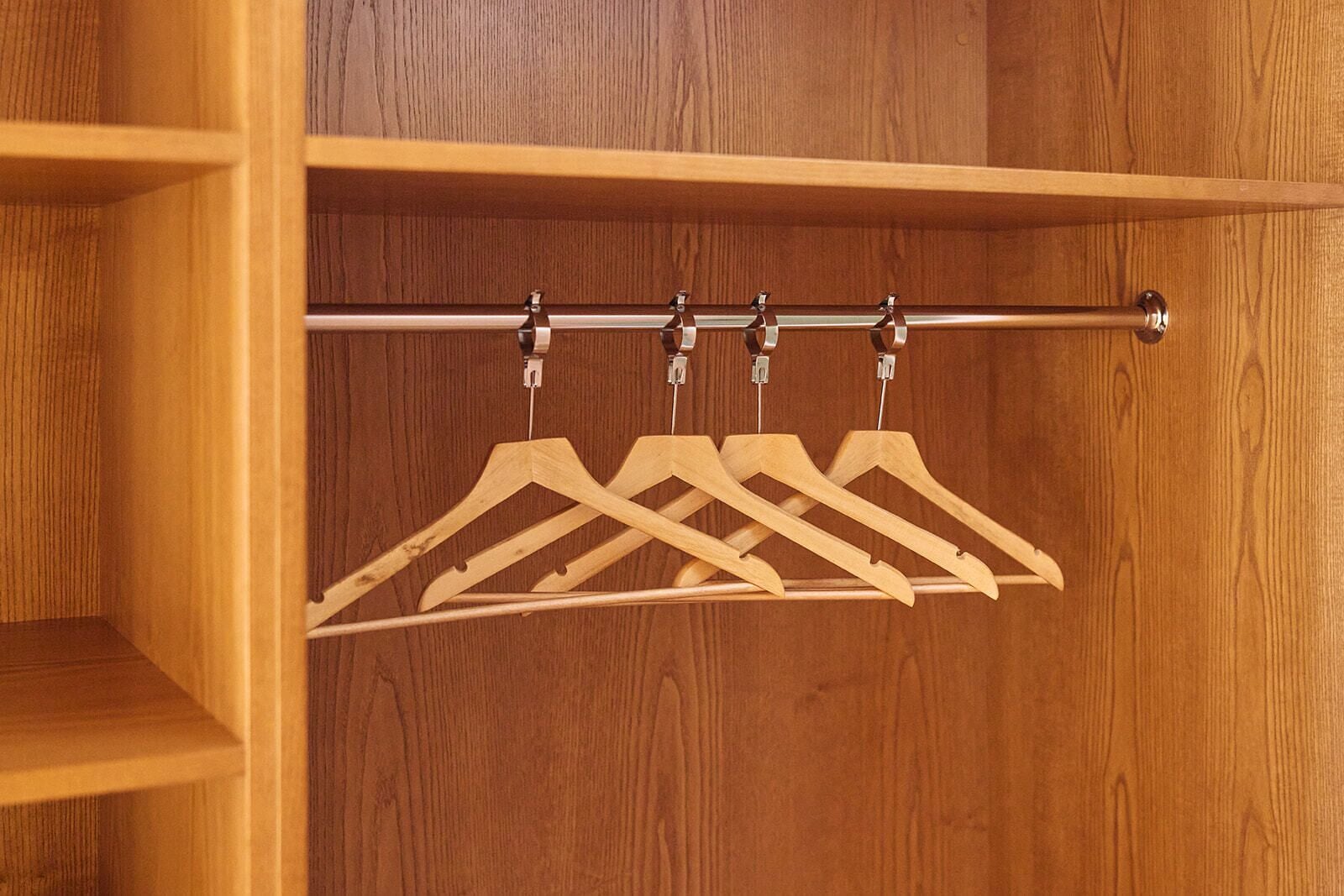 Ein Holzkoffer mit einer Metallstange und vier hölzernen Kleiderbügeln.