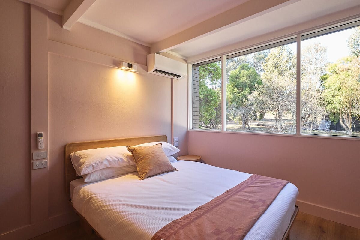 Un dormitorio con cama, ventana y aire acondicionado.