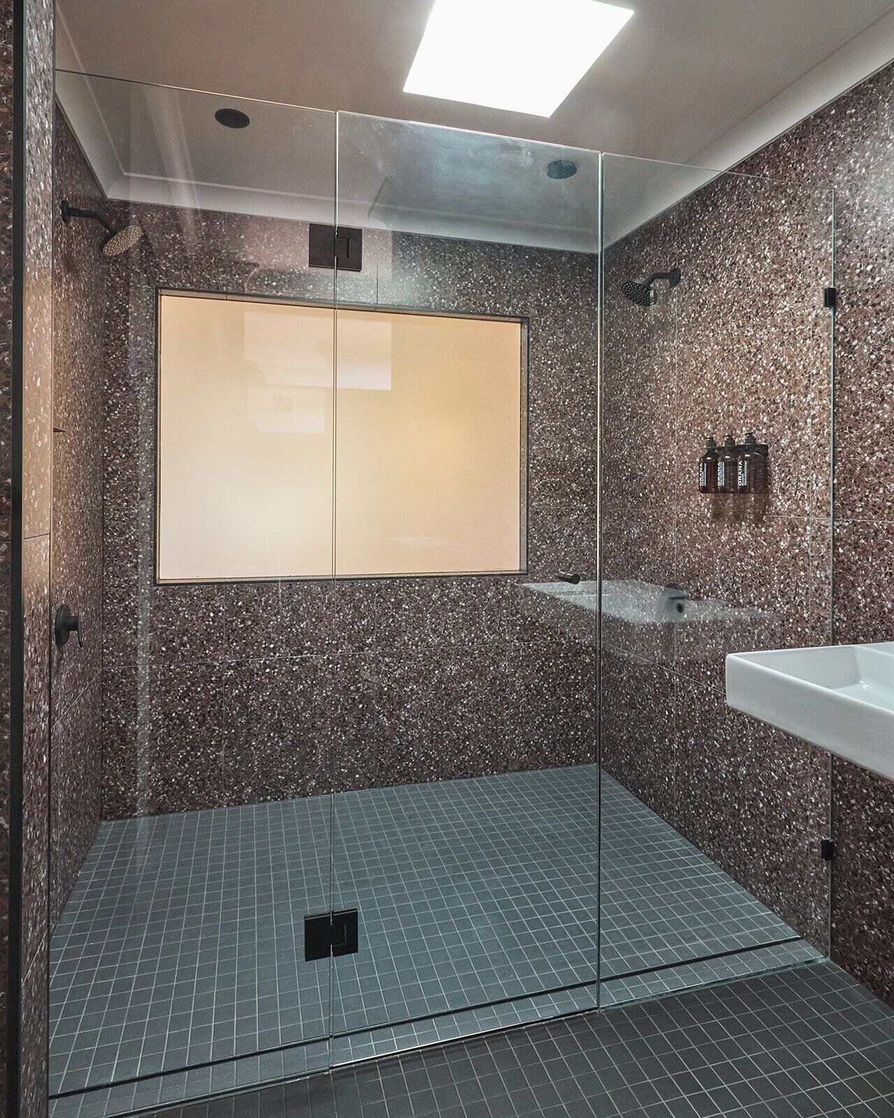 Un espace douche moderne doté d’une paroi en verre, d’un grand miroir et d’un sol carrelé.